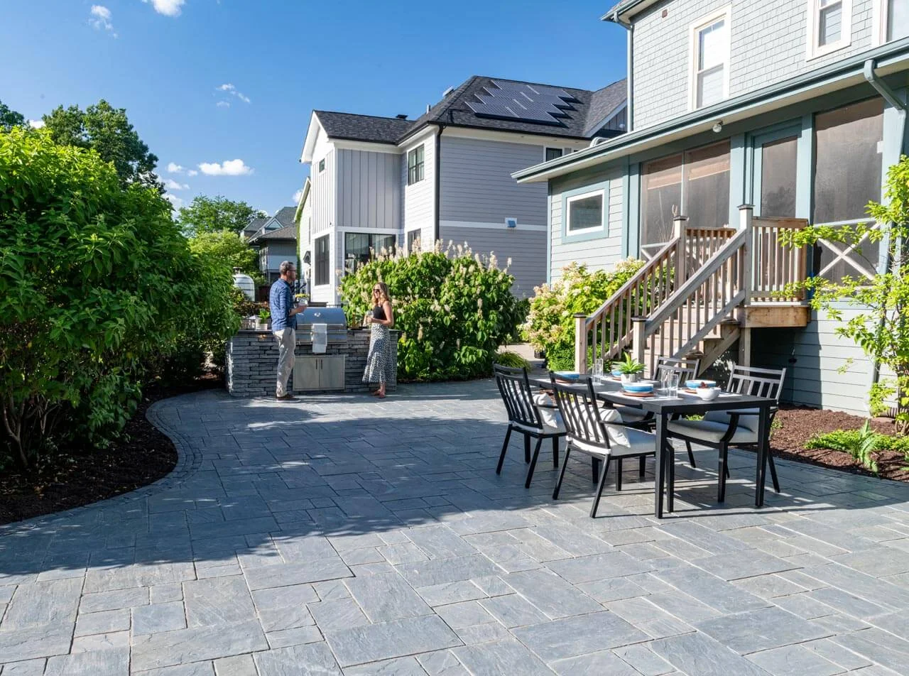 A luxury brick paver patio featuring an integrated fire pit, seating walls, and a professional outdoor kitchen setup A luxury brick paver patio featuring an integrated fire pit, seating walls, and a professional outdoor kitchen setup
