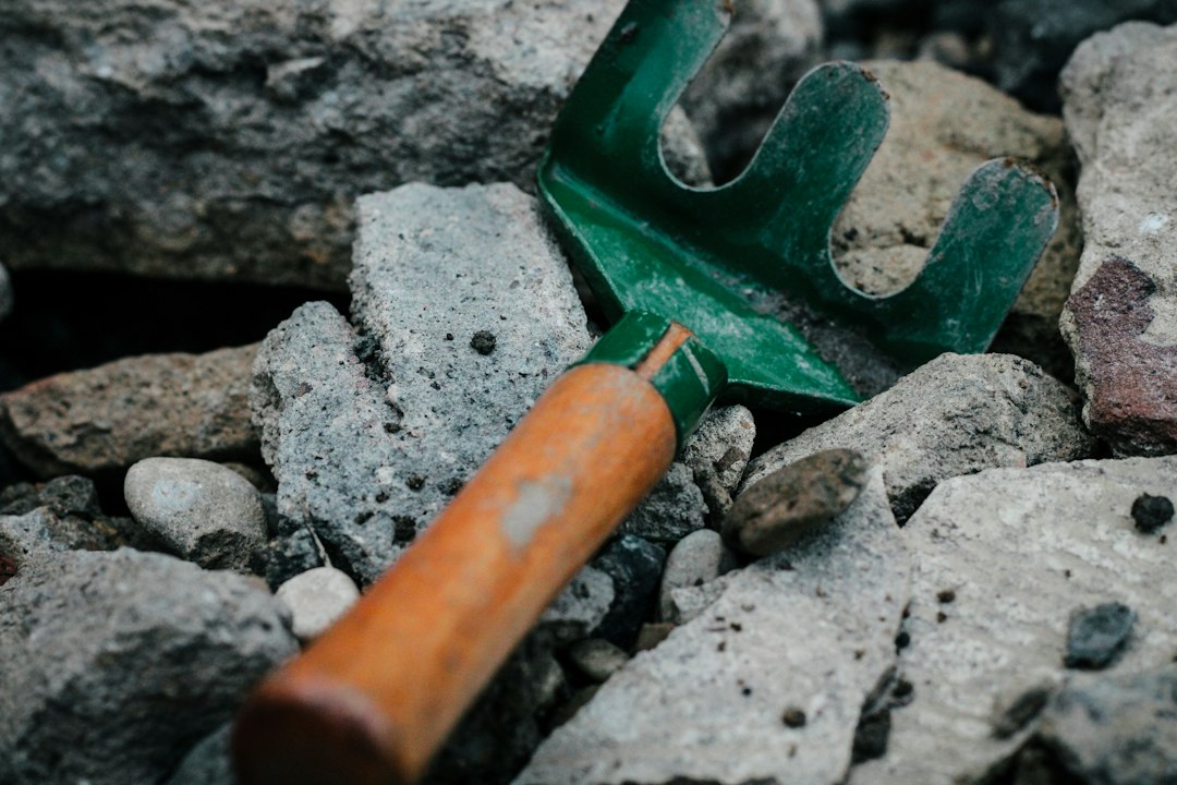 Tools needed for gravel repair including a steel rake, shovel, and hand tamper - fill potholes in gravel driveway
