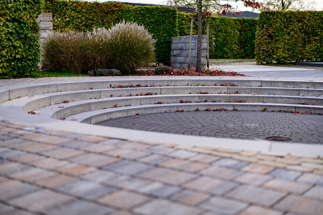 sunlit circular brick patio softening garden edges with lush green landscaping - circular brick patio designs pictures