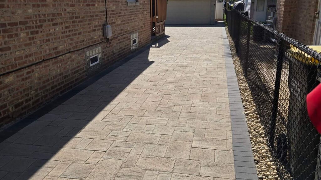 A paved driveway with stone pavers leads to a garage.