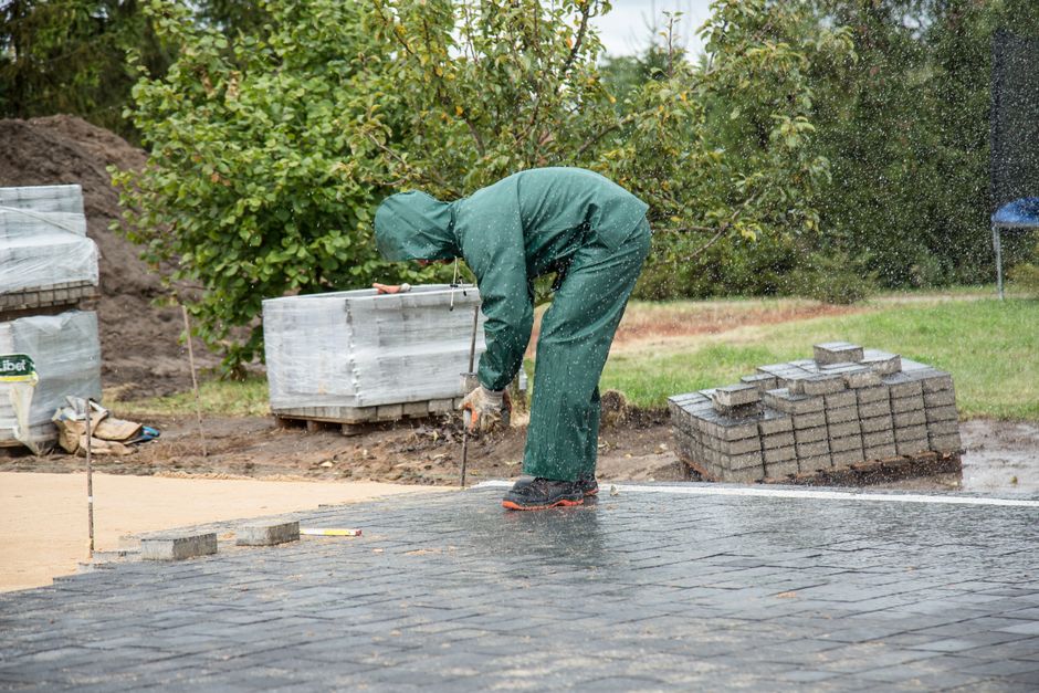 Essential tools for paver installation including plate compactor, level, and rubber mallet