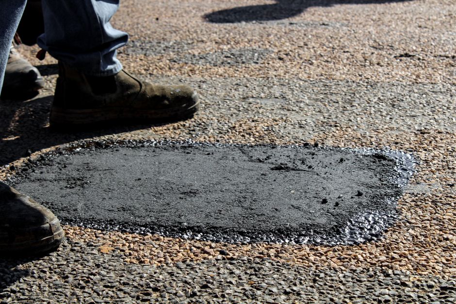 Newly repaired asphalt driveway surface showing clean compacted patch