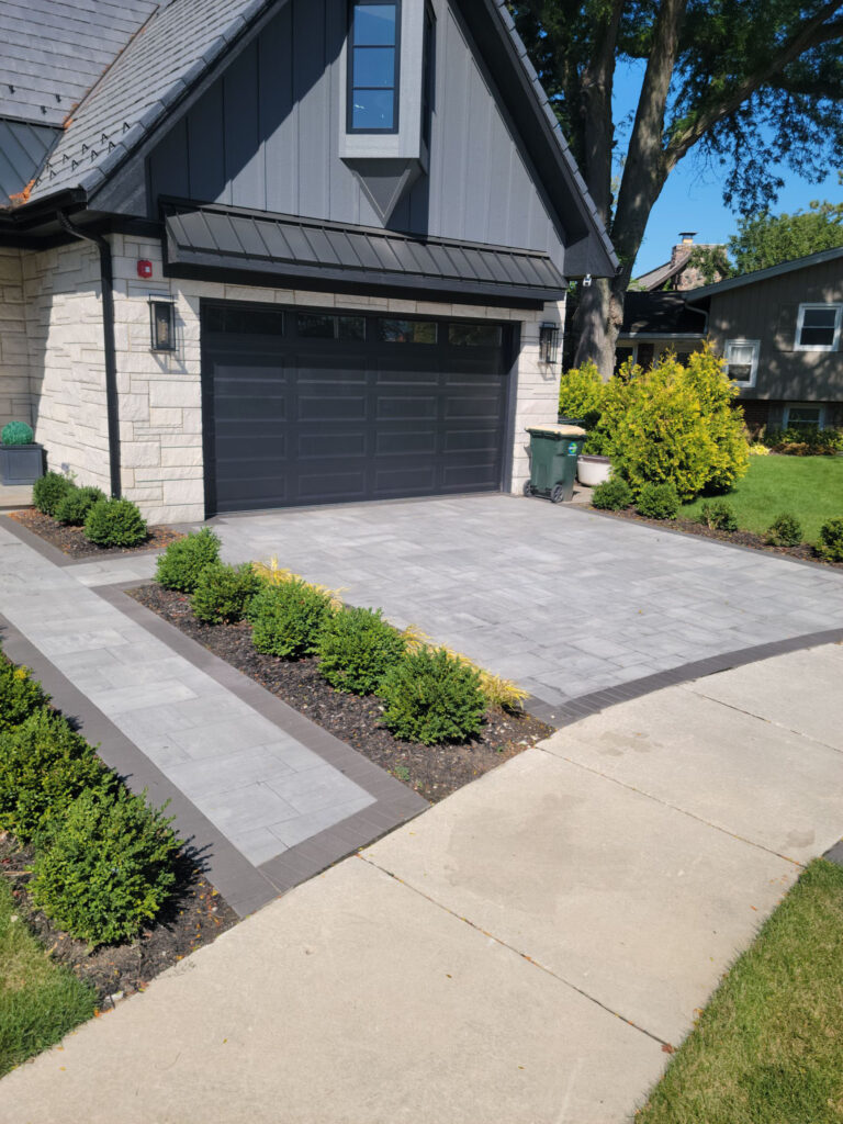 Modern house with a gray paver driveway and walkway.