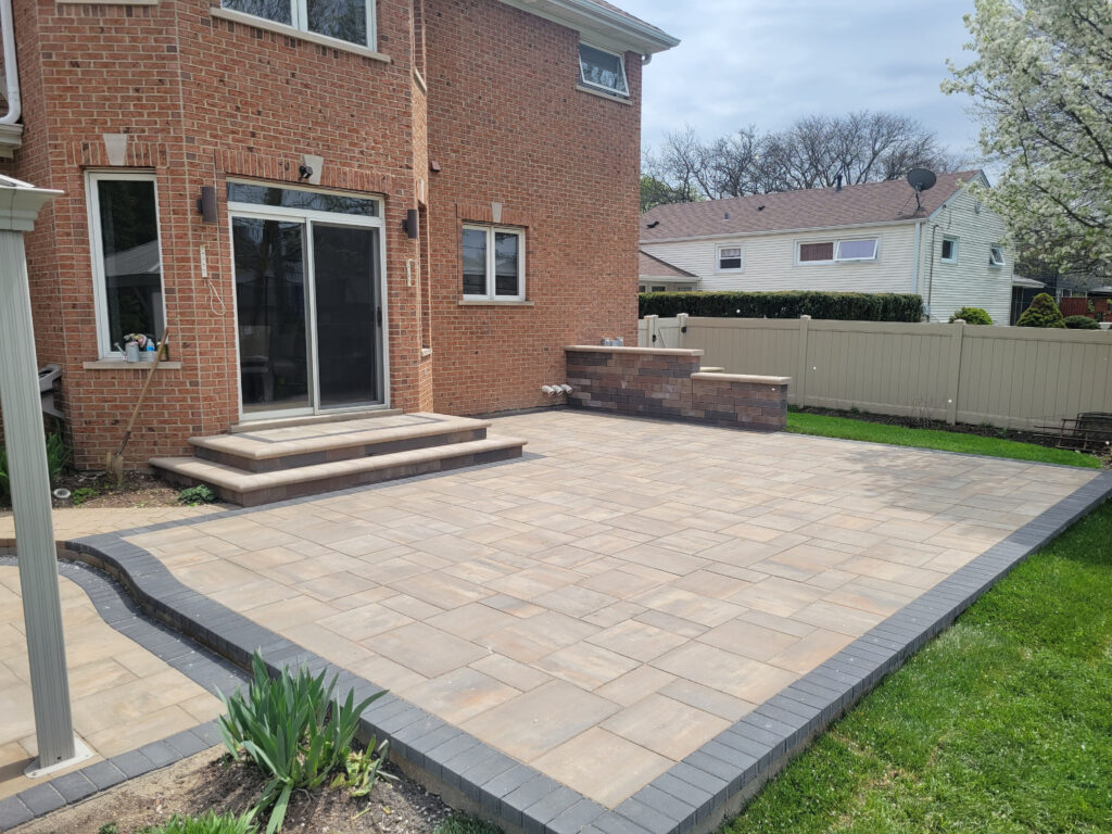 A newly paved patio with a brick house and a fence
