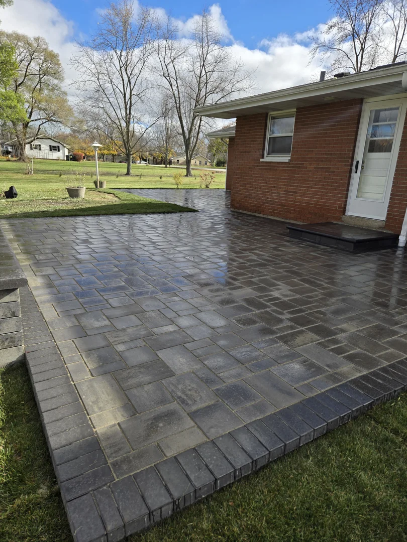A modern charcoal brick border contrasting with clean light grey flagstone pavers