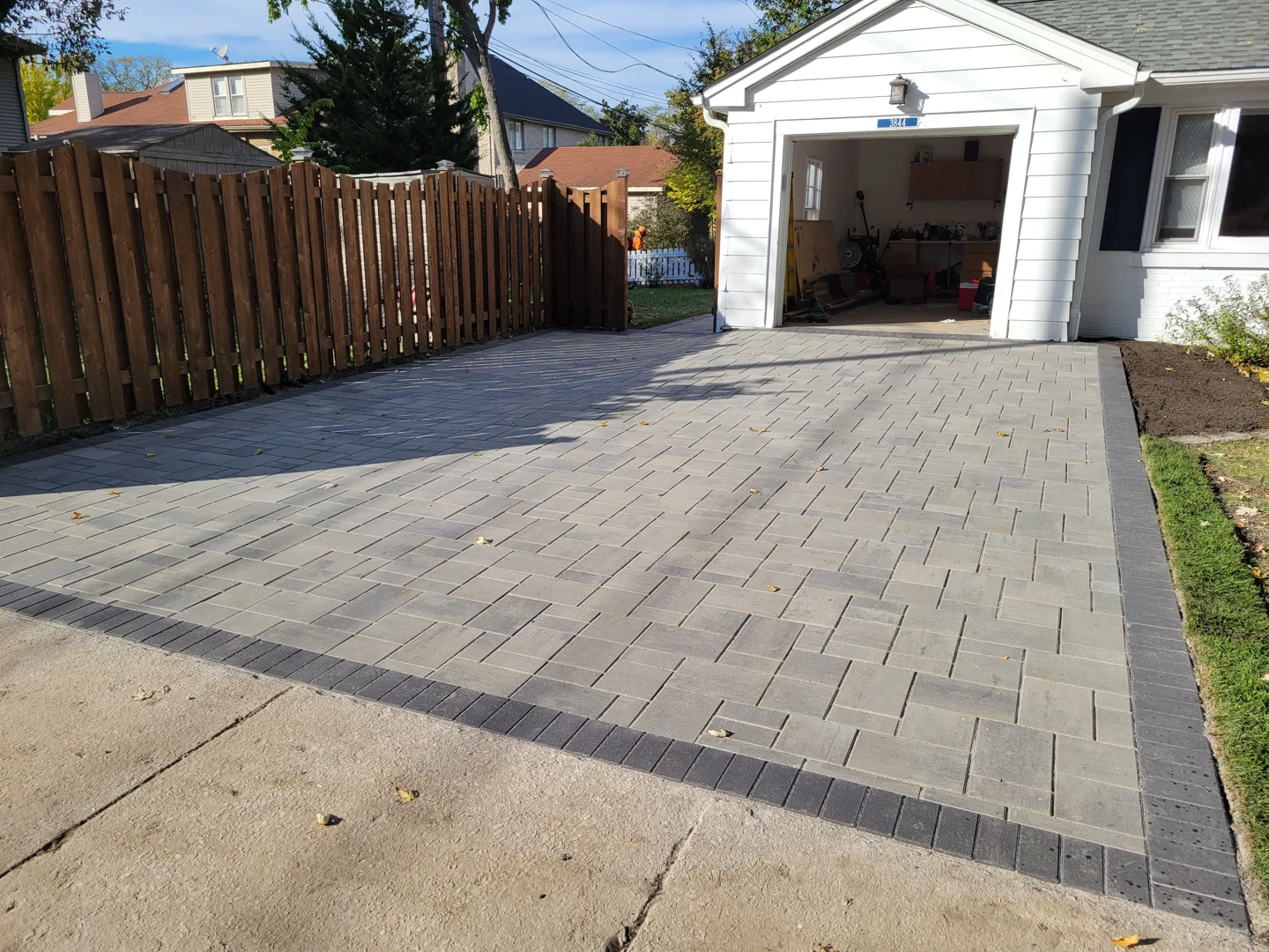 Professional installation crew laying Unilock brick pavers on compacted gravel base