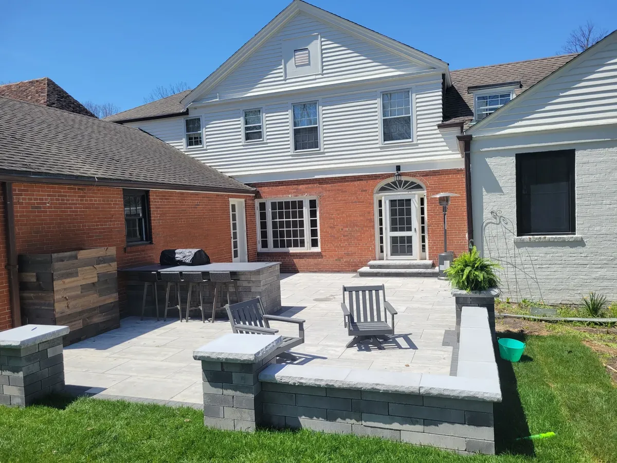 U-shaped outdoor brick kitchen bar on a paver patio with bar seating during golden hour